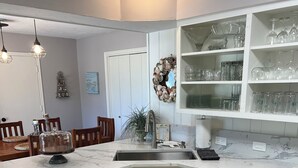 A kitchen with white cabinets, a Bosch dishwasher, and a marble countertop. - Hideaway @ Knob Hill (Little Elm)