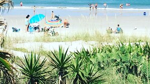Ein Strand mit Menschen, Sonnenschirmen und Liegestühlen.
