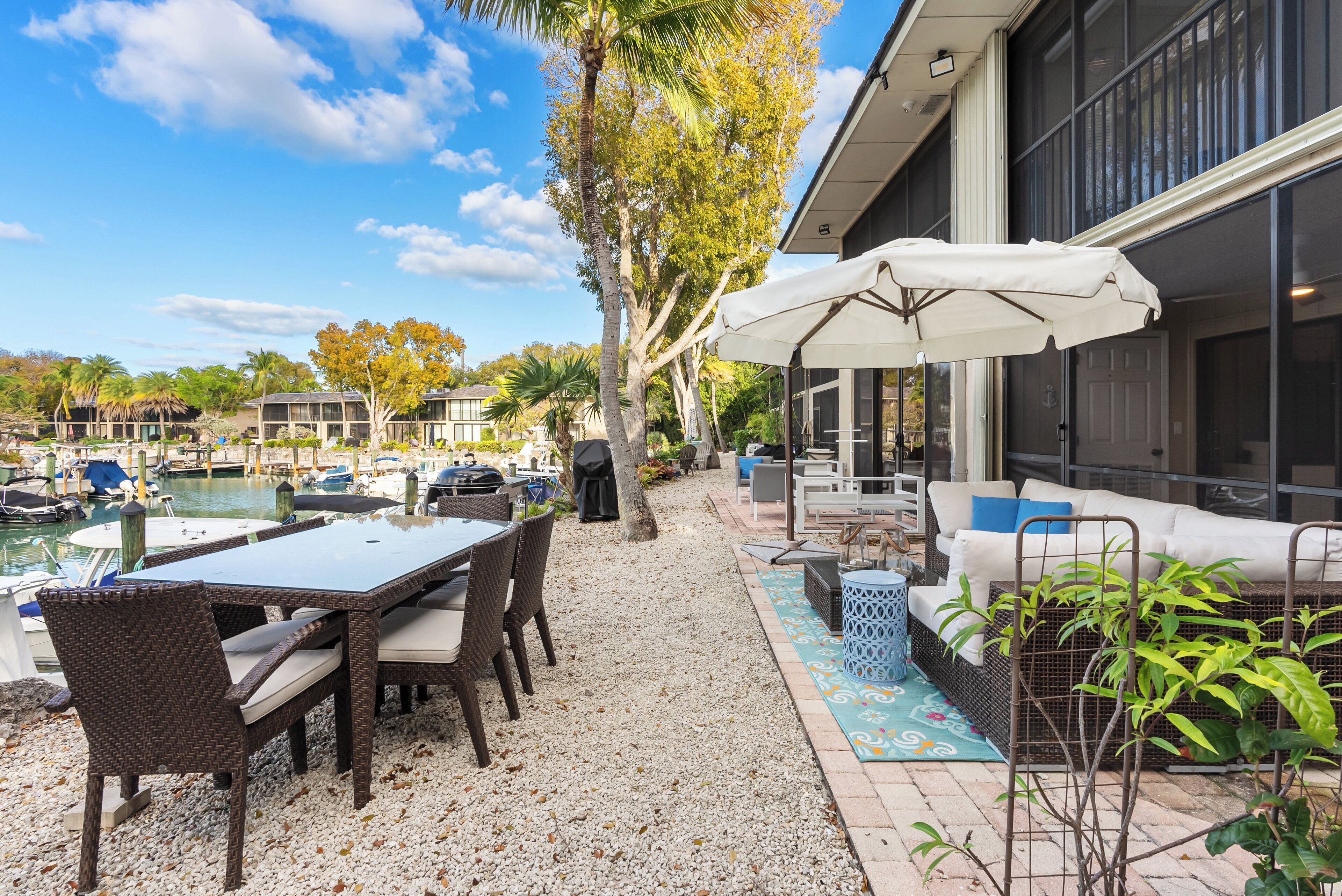 A patio with a table and chairs, a covered seating area, and a view of a marina with boats.