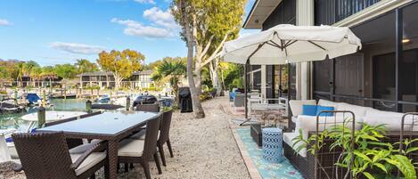 A patio with a table and chairs, a covered seating area, and a view of a marina with boats.