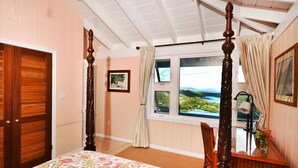 A bedroom with a four-poster bed, a window with a view, a wooden door, and a framed picture on the wall. - Beautiful Cottage w/Stunning View, Backup Power, Hot Tub, Family or 2 Couples  (Coral Bay)