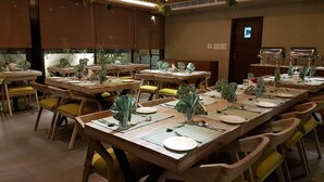 A dining area with multiple tables set for service, equipped with chairs, plates, cutlery, and glassware. - Hotel Sumaditya (Jaipur)