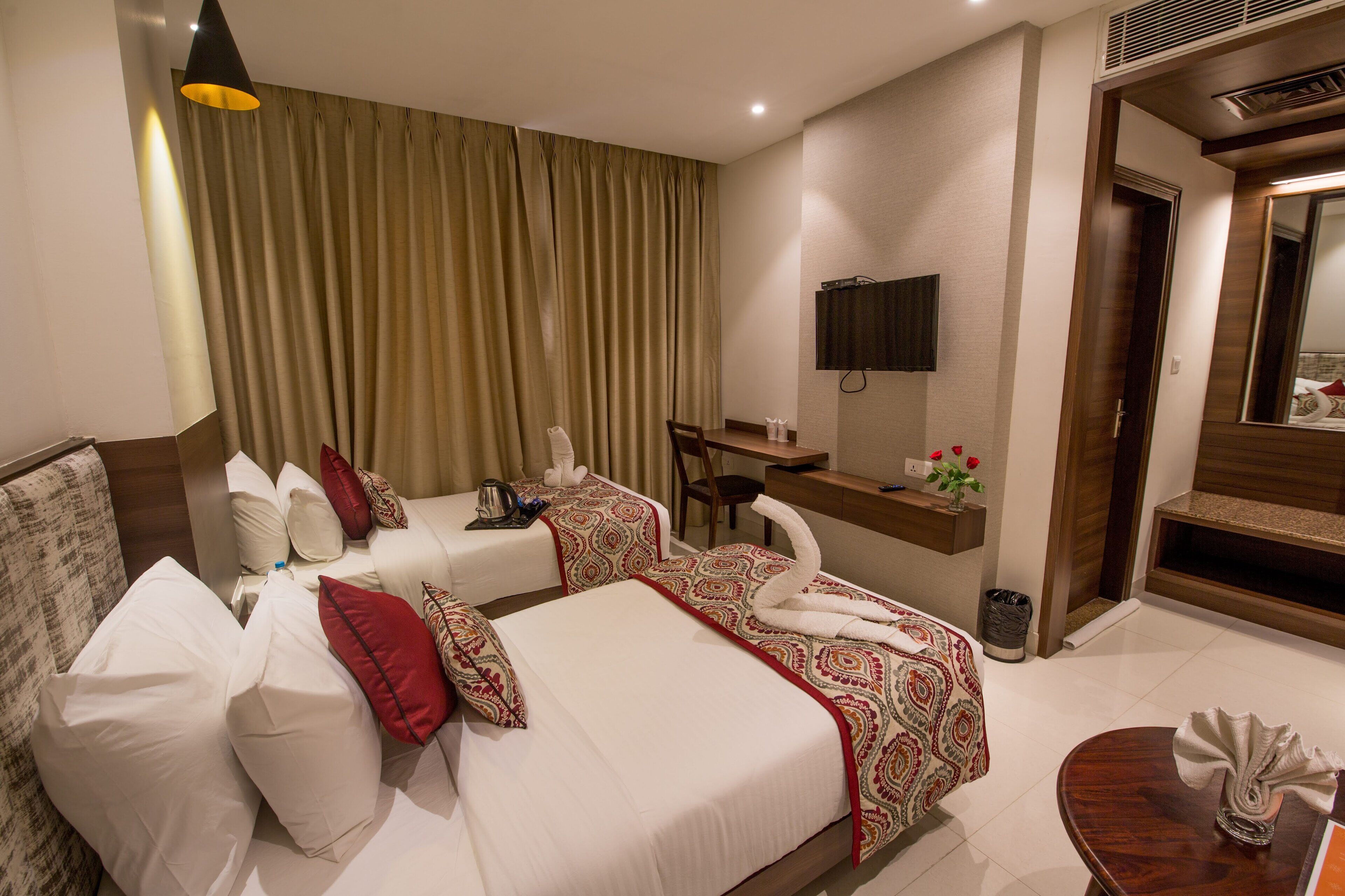 Una habitación de hotel con dos camas, un escritorio, una silla, un televisor y un baño.