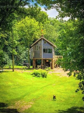 Situated in a lush environment, this house offers a unique living space with multiple windows and a cozy porch area.