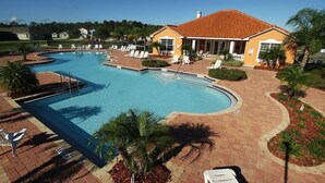 A swimming pool with lounge chairs and a building with a red roof. - 5 Stars House With WiFi, Game Room, Private Heated Spa & Pool In a Gated Area (Kissimmee)