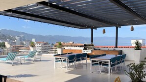 An outdoor patio with a grill, seating area, and a view of the sea.
