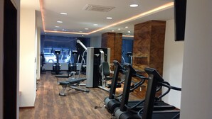 A gym with treadmills, weight machines, and a mirror wall.