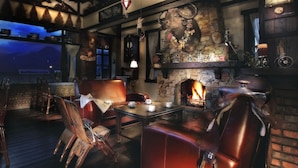 Um pub acolhedor com assentos de couro, lareira de pedra e decoração rústica.
