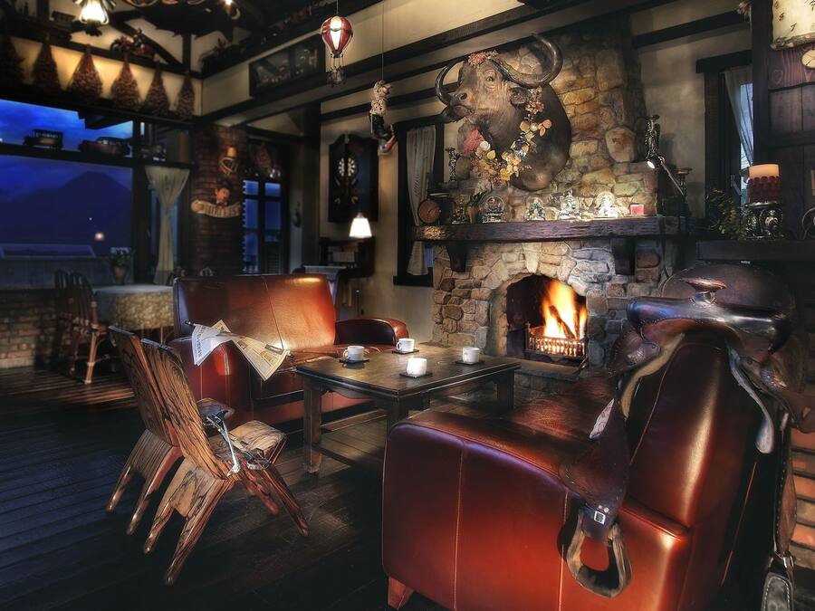 Un pub acogedor con asientos de cuero, chimenea de piedra y decoración rústica.