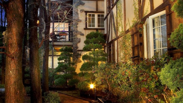 Um edifício tradicional em estilo europeu, com fachada de pedra, vigas de madeira e um caminho que leva a porta.