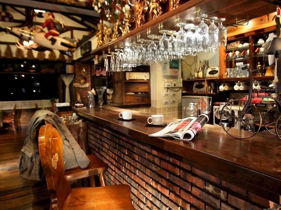 A bar area with a brick wall, wooden counter, and hanging glassware.