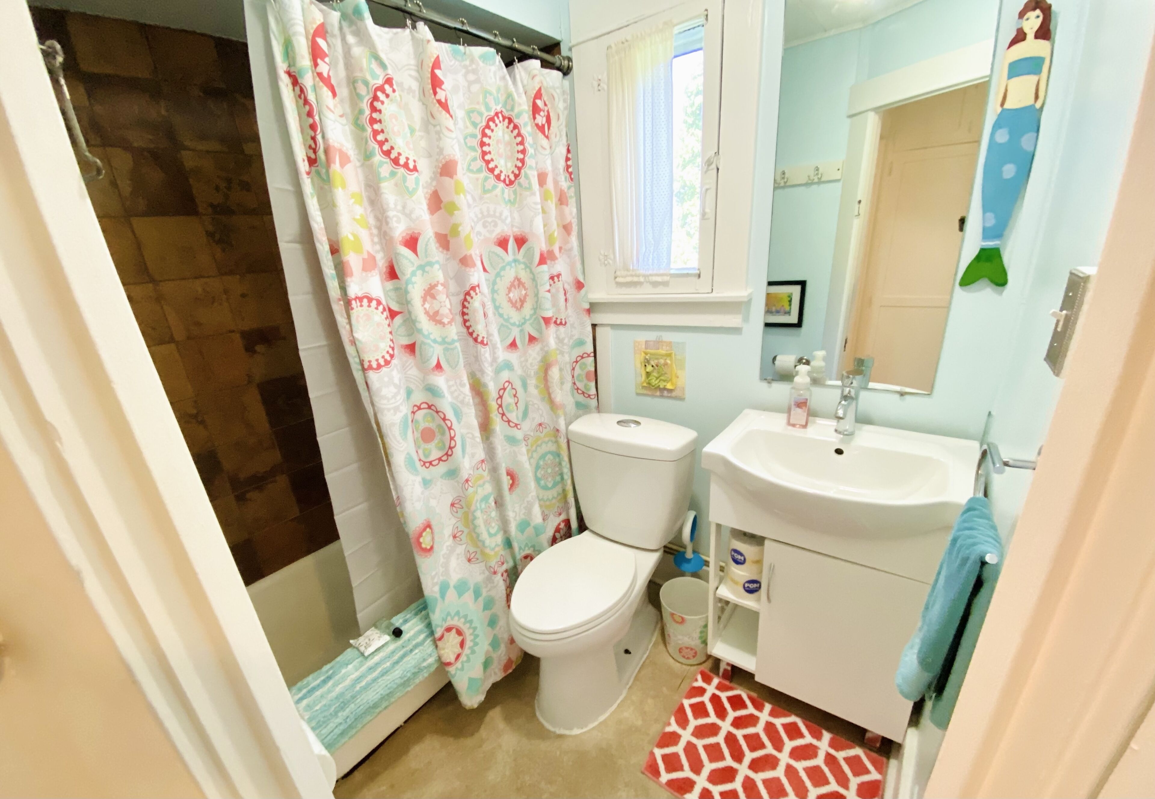 A bathroom with a toilet, sink, and shower curtain.