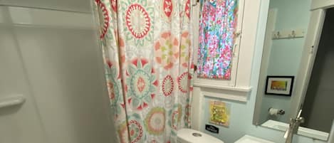 Un baño con bañera, inodoro, lavamanos y cortina de ducha.