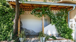 Een overdekt buitengebied met een stenen muur, plantenbakken en een houten pergola.