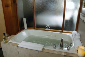 A bathroom with a bathtub, a window with frosted glass, a towel, and a candle. - Great Condo in Excellent Location - Waterfront Building - Seaside (Ucluelet)
