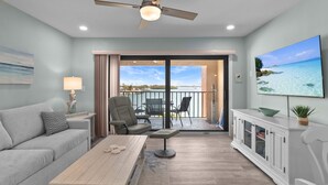 A modern living room with a sofa, coffee table, and a balcony with outdoor furniture. - Bay Watch - Waterfront - Walk to beach and restaurants - Dock your boat (Englewood)