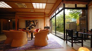 Een traditionele Japanse kamer met tatami vloerbedekking, een lage tafel en uitzicht op de omgeving.