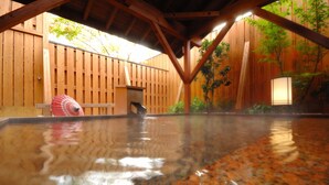 Een houten terras met een jacuzzi, houten wanden en een metalen hekwerk.