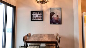 A dining area with a wooden table and chairs, a chandelier, and framed pictures on the wall.