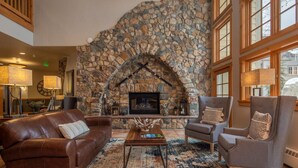 A cozy living room with a stone fireplace, leather sofas, and a coffee table. - 8562 | Pool & Hot tub OPEN, Steps to Gondola. (Keystone)