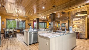 Une cuisine spacieuse dotée d’un plancher en bois, d’un îlot central avec un évier et d’un coin repas avec des tables et des chaises.