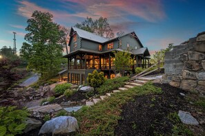 A large, two-story house with a stone exterior and a wrap-around porch.