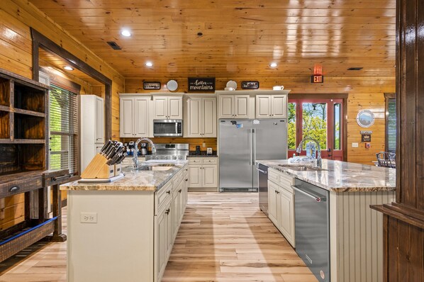 A modern kitchen with white cabinets, stainless steel appliances, and a wooden floor.