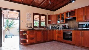 A kitchen with wooden cabinets, a microwave, an oven, and a window overlooking a patio area.
