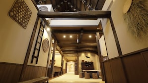 A traditional interior with wooden beams, tatami mats, and a central corridor leading to a reception area. - Onyado Yuinosho (Shirakawa)