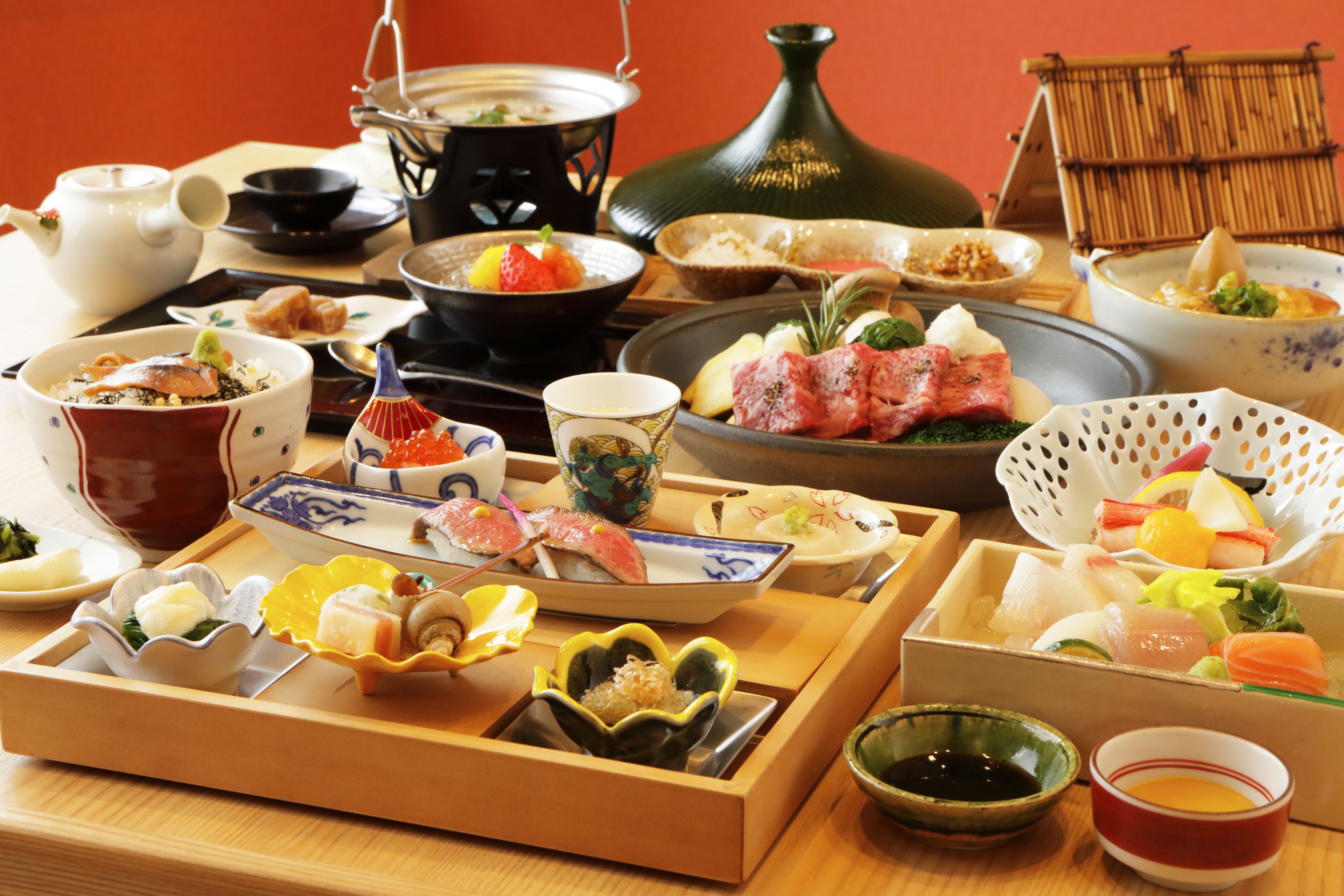 A variety of Japanese dishes arranged on a wooden table, including sushi, sashimi, and other traditional foods.