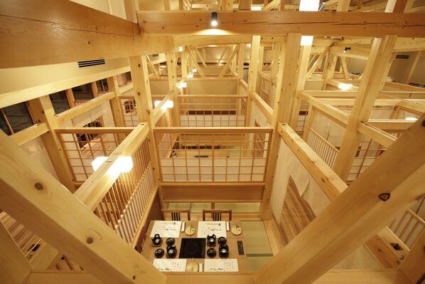 A multi-level wooden structure with a central open area featuring tables and chairs, surrounded by wooden railings and multiple levels of balconies. - Onyado Yuinosho (Shirakawa)
