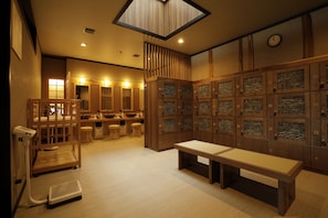 A room with wooden lockers, a bench, a scale, and a counter with stools.