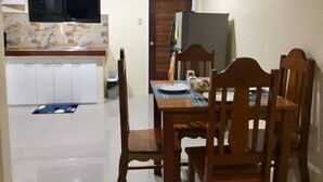 A compact kitchen with white cabinets, a tiled backsplash, and a built-in TV. - Cris Place Dumaguete (Valencia)