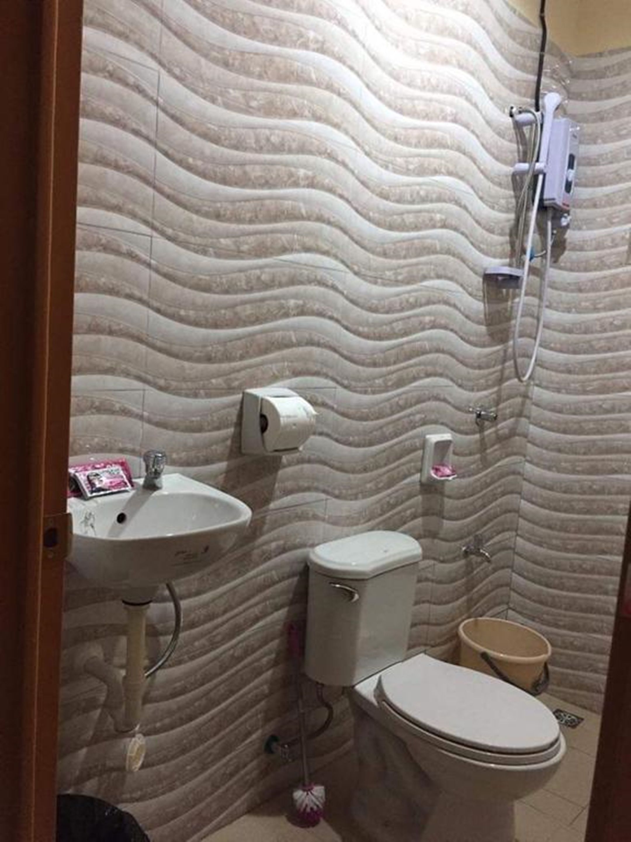 Une salle de bain avec un mur à motifs, un lavabo, des toilettes et une douche.