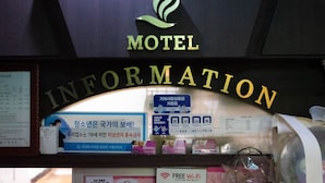 Mostrador de información de motel con un logotipo, un cartel que anuncia Wi-Fi gratuito y varios folletos informativos.