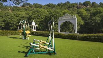 A well-maintained park with exercise equipment, a white gazebo, and a decorative archway.