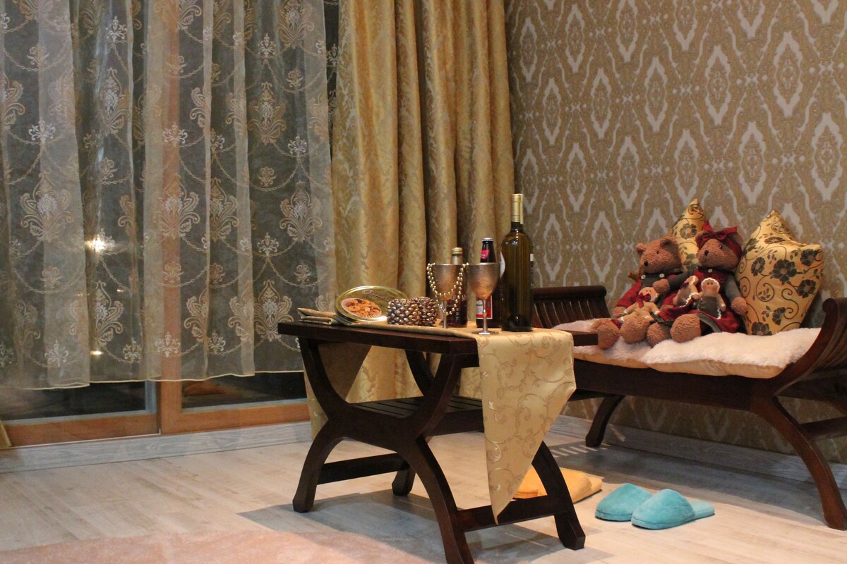 A dining area with a table set for two, a chair, and a sofa with cushions.