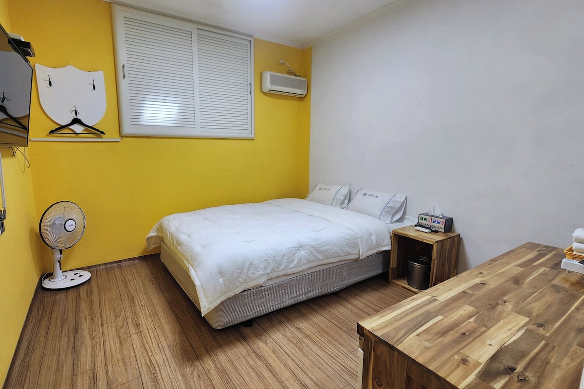 Un dormitorio con cama, mesita de noche y un escritorio de madera.