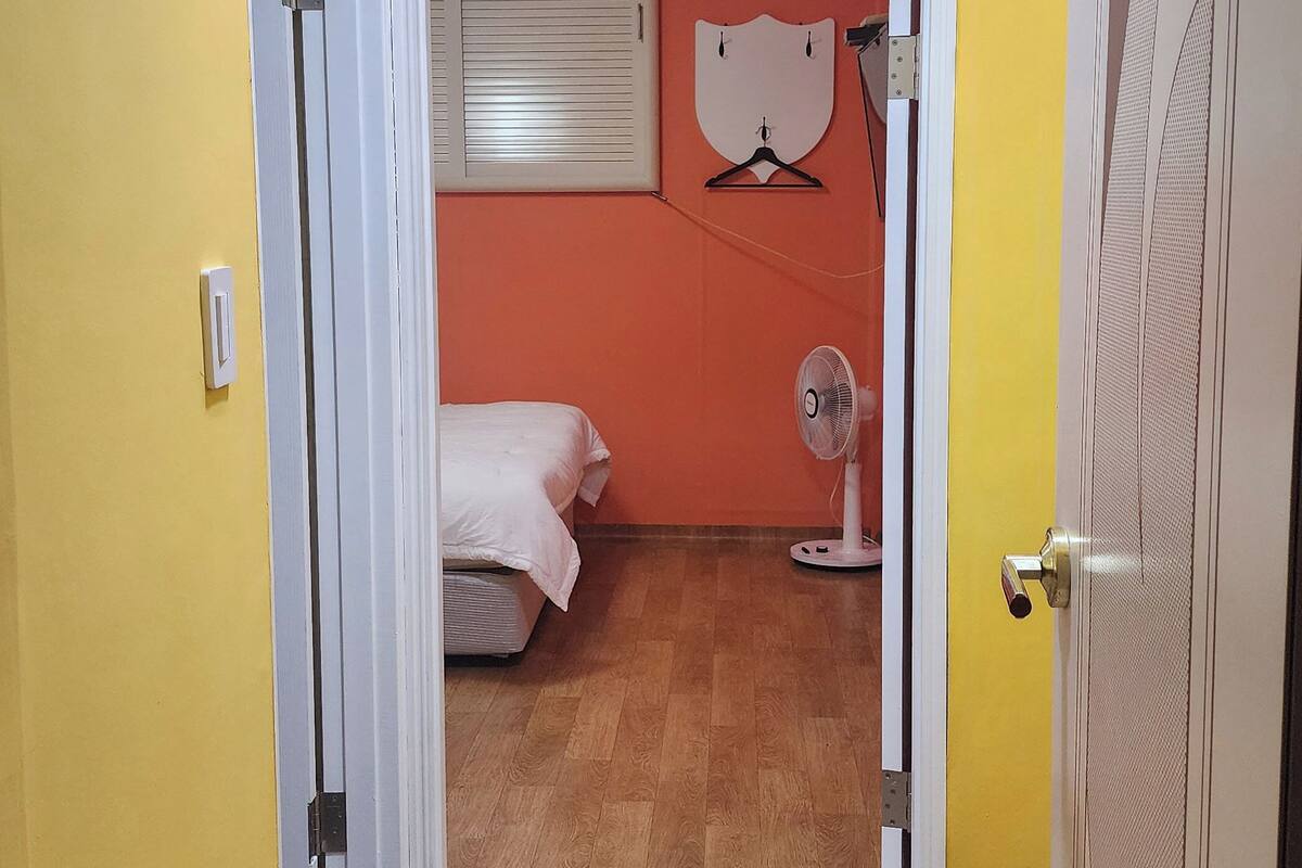 Una habitación con cama, ventilador y puerta que da a otra habitación.