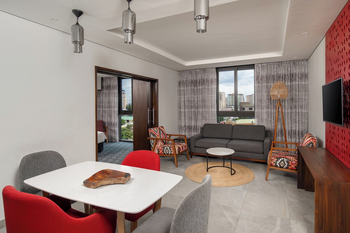 Un salon moderne comprenant un canapé, des fauteuils, une table à manger et un téléviseur.