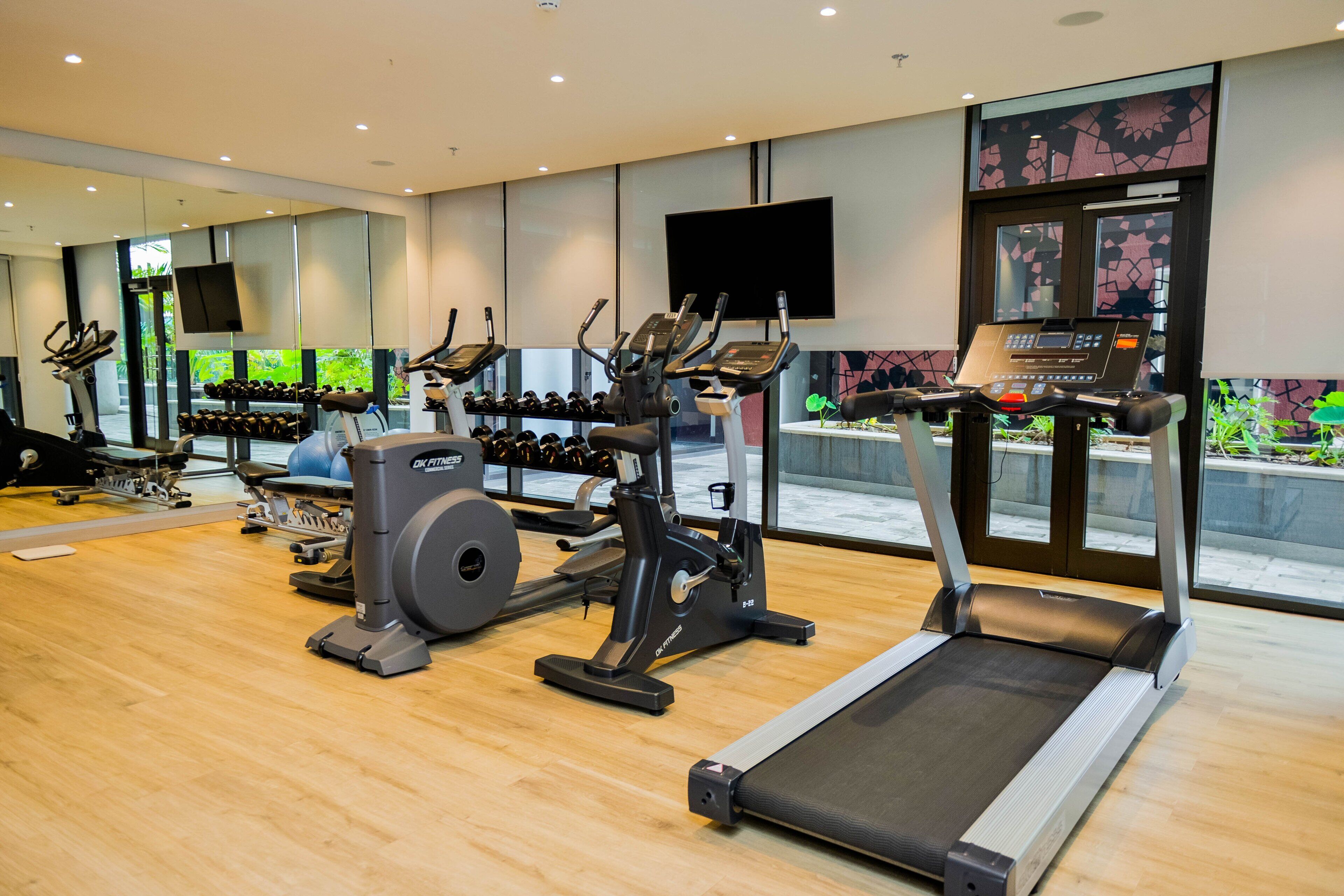 Une salle de sport moderne équipée de tapis de course, de vélos elliptiques et de postes d'entraînement avec poids.