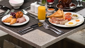 A breakfast table with various dishes, a glass of orange juice, and a vase with flowers. - Crowne Plaza Dar es Salaam by IHG (Dar es Salaam)
