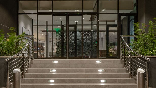 A set of stairs leading to a building entrance with glass doors and a metal railing. - Crowne Plaza Dar es Salaam by IHG (Dar es Salaam)