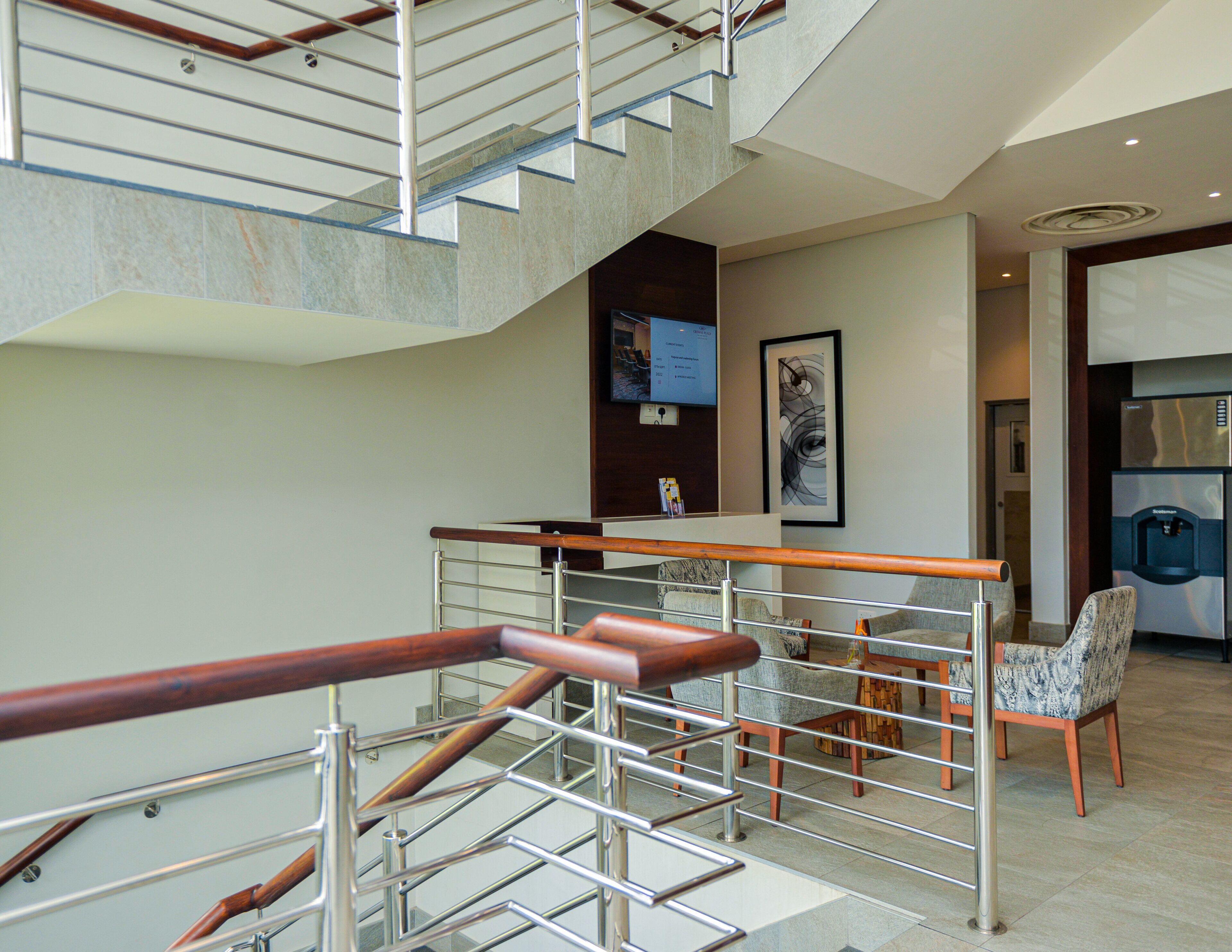 A modern interior with a staircase, a reception desk, and a seating area.