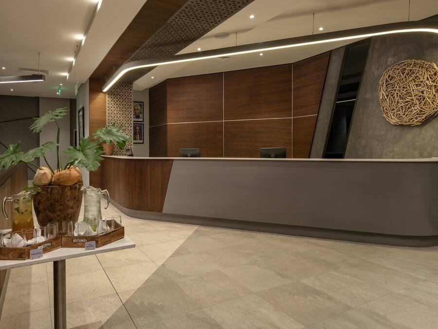 A modern reception area with a curved desk, a decorative wall piece, and a plant arrangement.