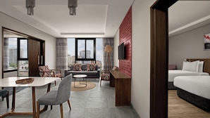 A modern hotel room with a dining area, a sofa set, a TV, and a bed. - Crowne Plaza Dar es Salaam by IHG (Dar es Salaam)