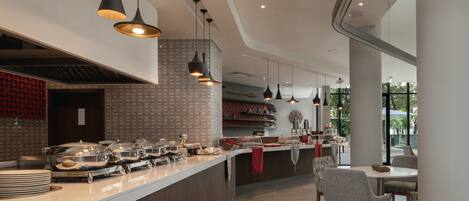 A modern restaurant with a long counter, pendant lighting, and a view of the outdoors.