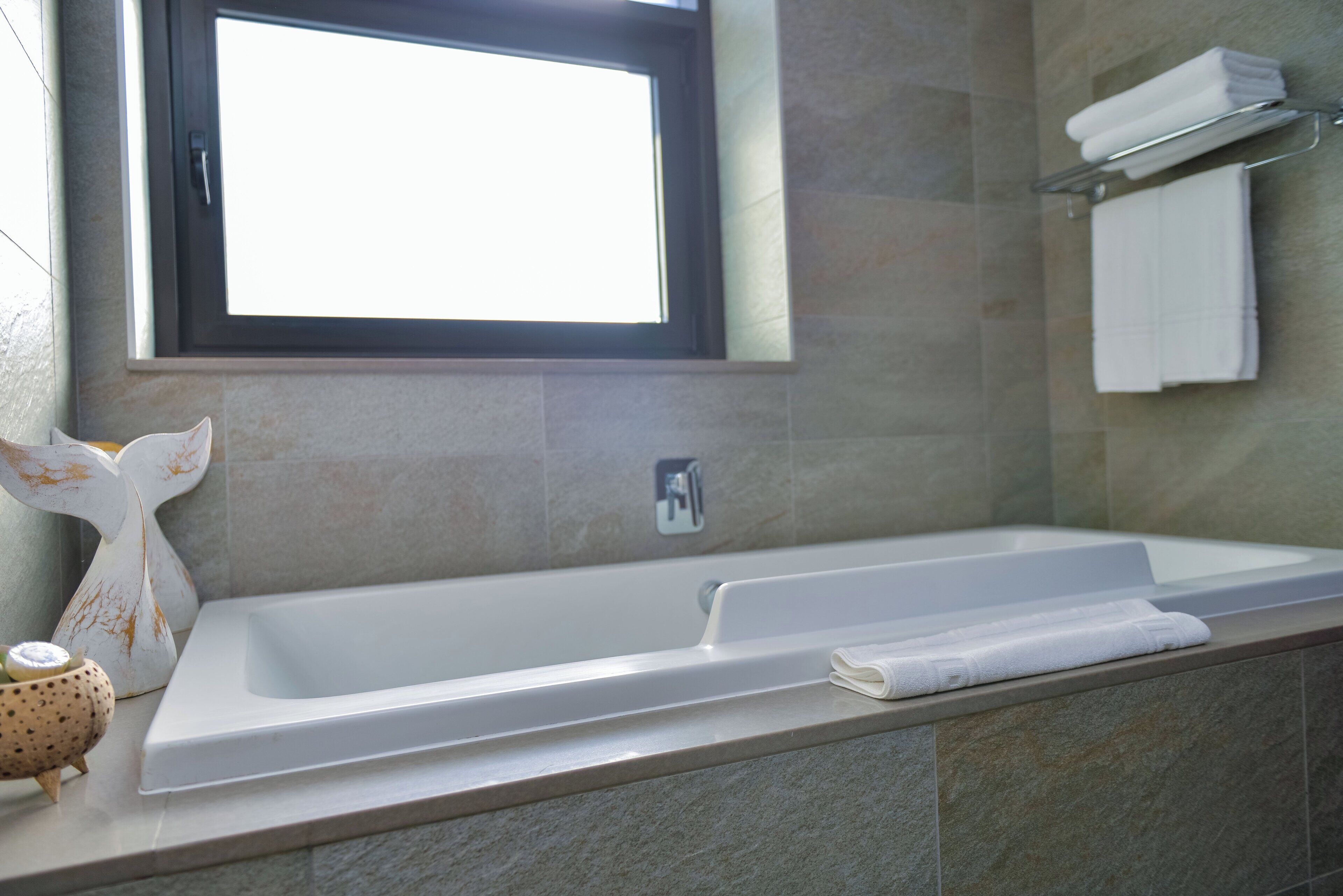 Un baño moderno con bañera, ventana y perchero.