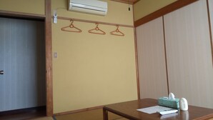 Una stanza con un tavolo in legno, un astuccio per fazzoletti e un telecomando. Si vede un armadio in legno e una porta con un attaccapanni.