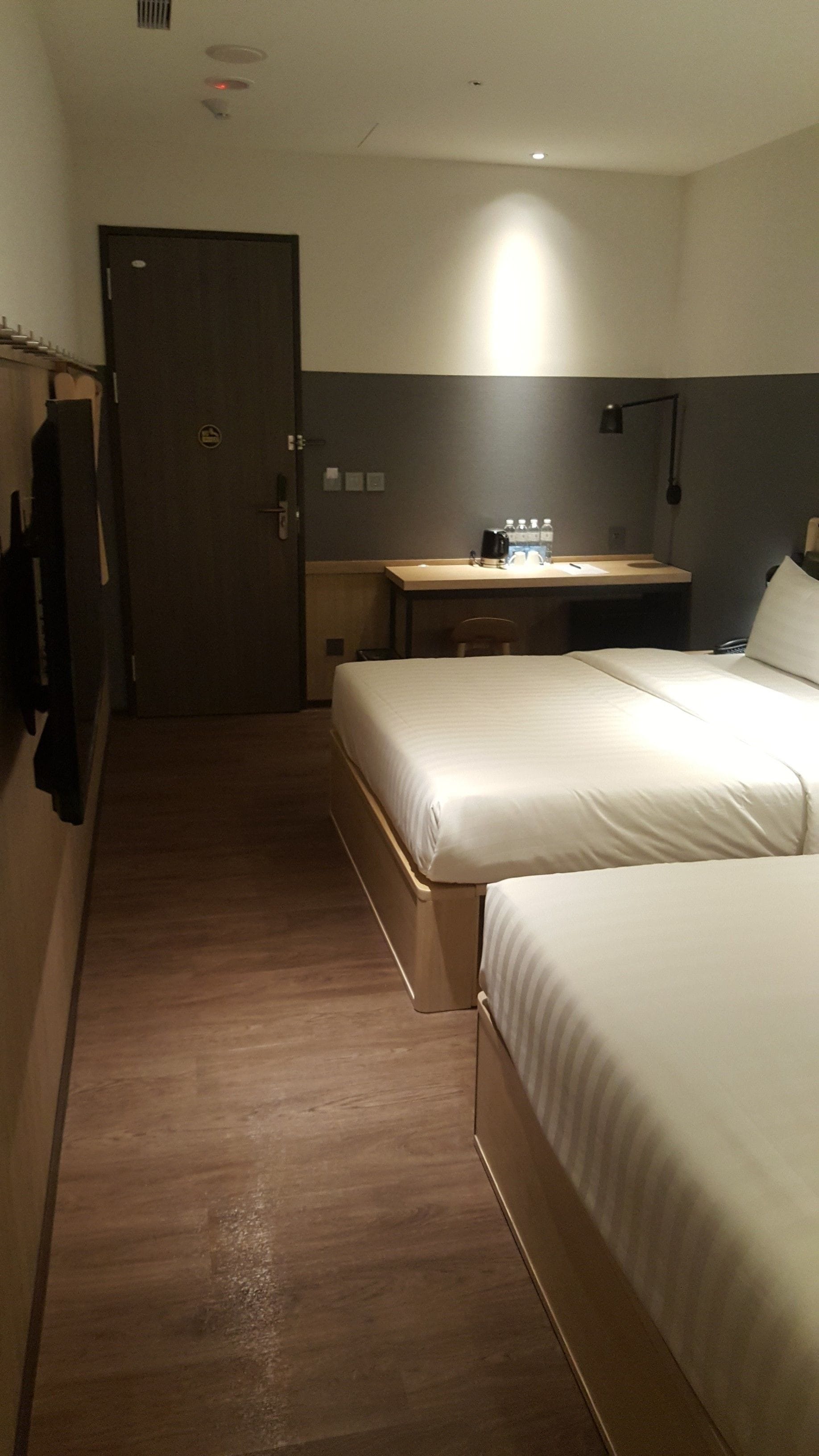 Une chambre d’hôtel avec deux lits, un bureau, une chaise et une porte.